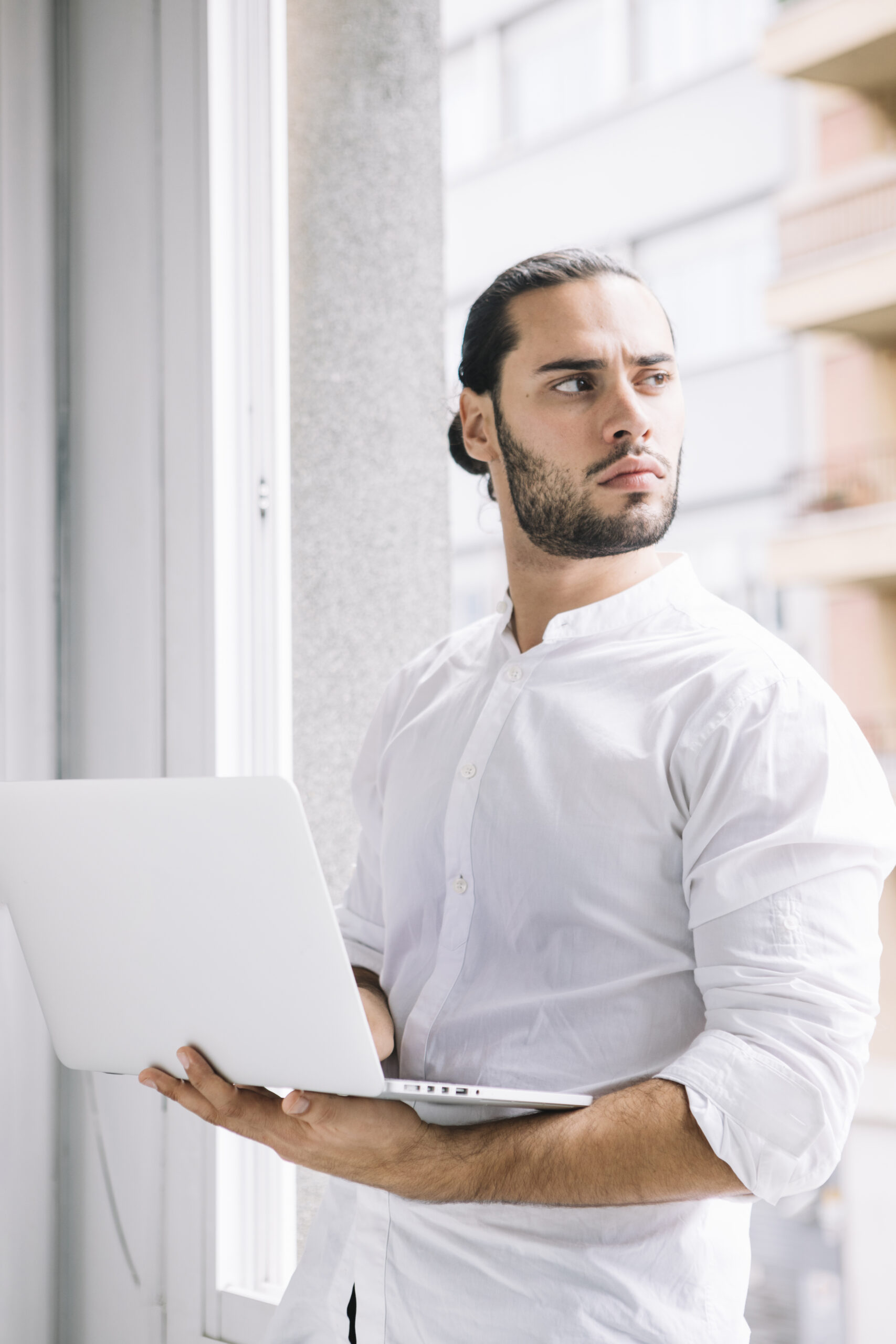 young-handsome-man-holding-laptop-device-hand-looking-away